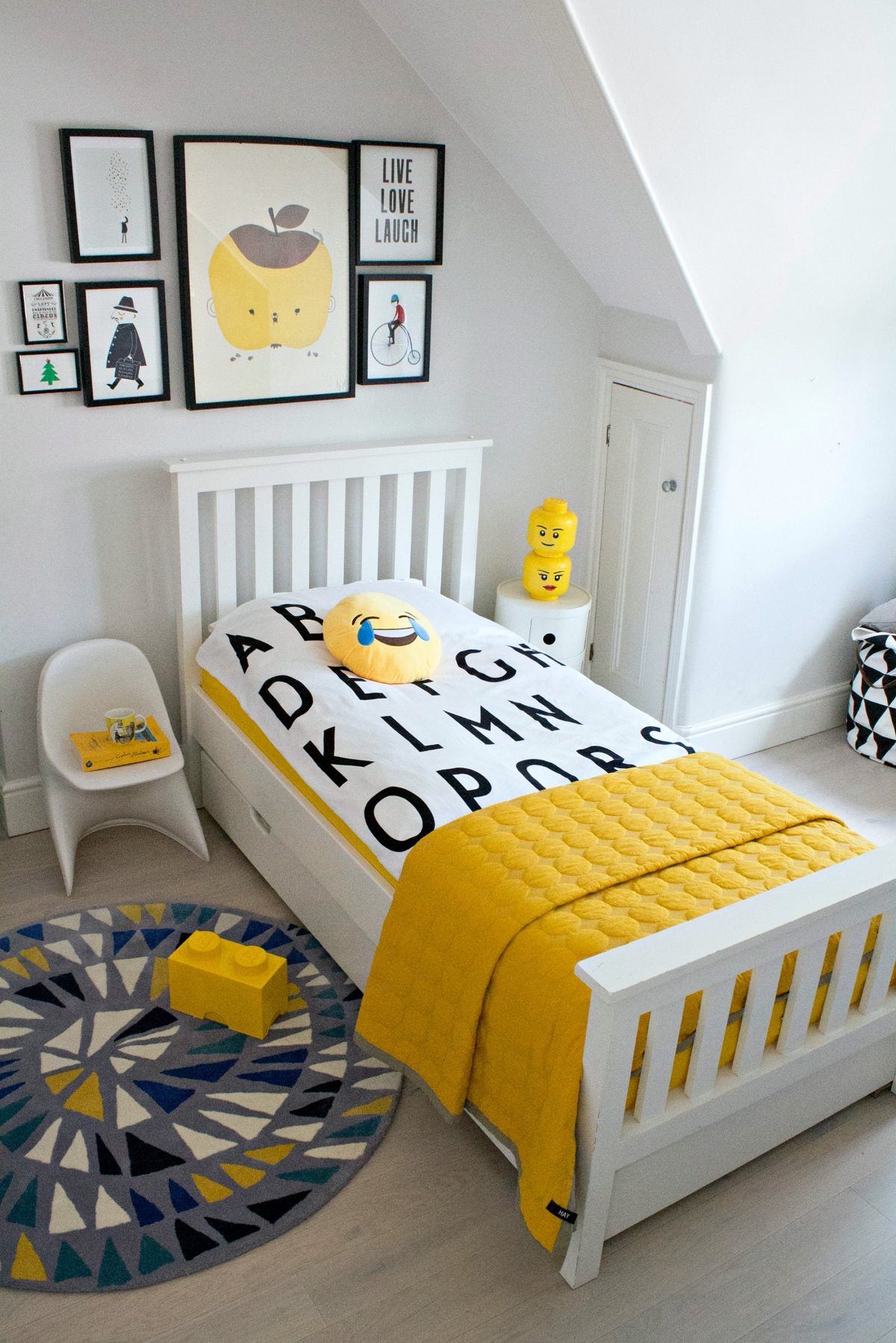 دکوراسیون اتاق کودک پسر شیک که روی تخت آن روتختی به طرح حروف الفبای انگلیسی پهن شده است